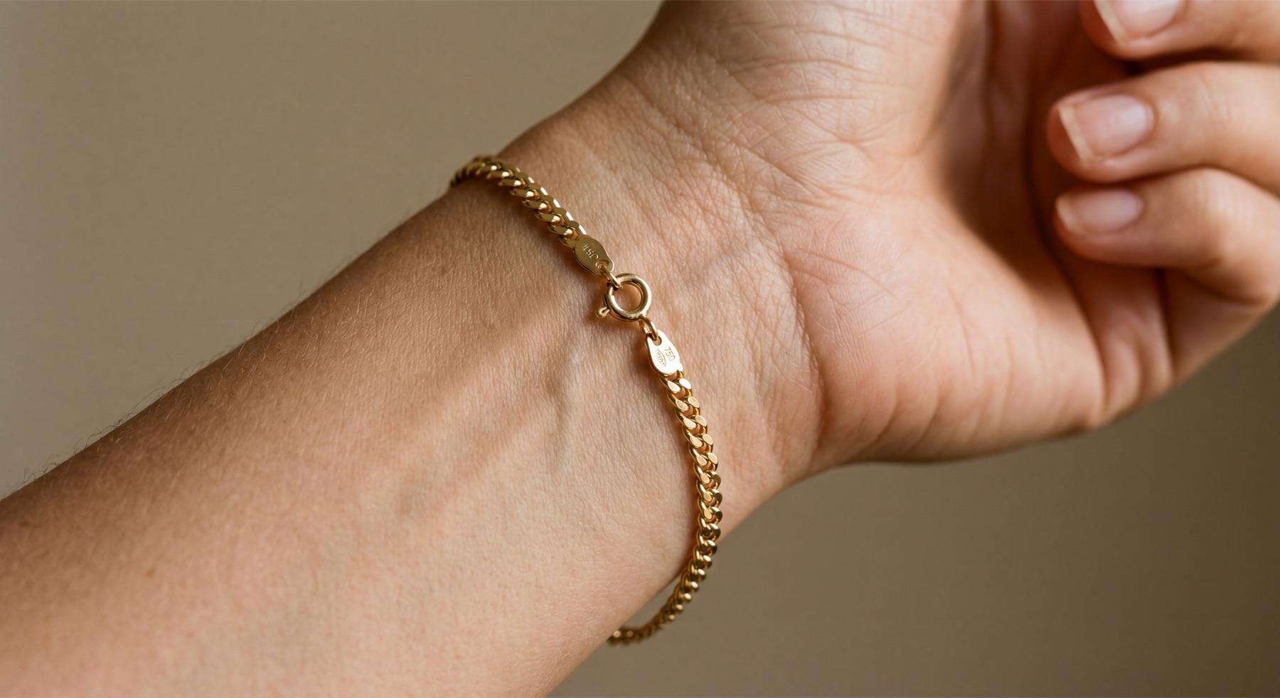 Gold chain bracelet worn on wrist — detail shot